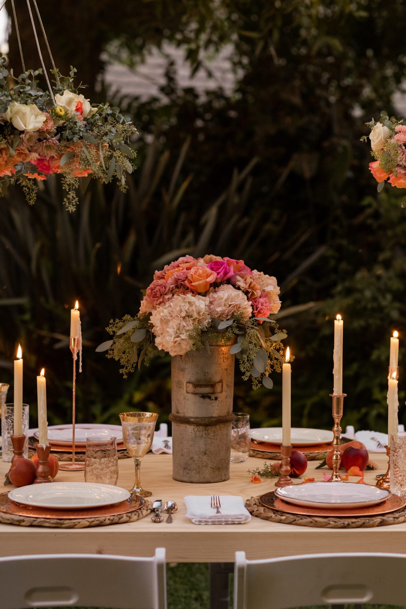 A handmade flower crown made from a vintage lampshade, oasis, and fresh flowers hanging on top of a magical table set for 40 guests.