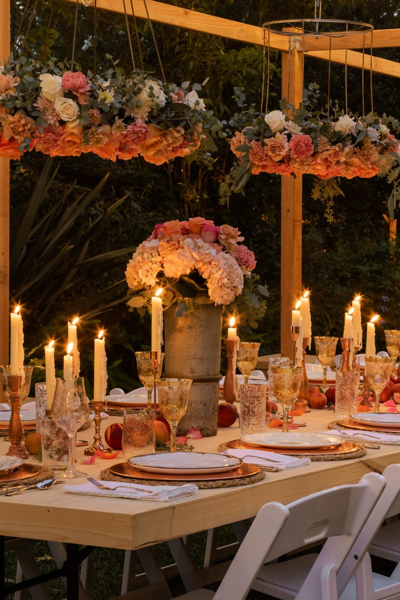 A handmade flower crown made from a vintage lampshade, oasis, and fresh flowers hanging on top of a magical table set for 40 guests.