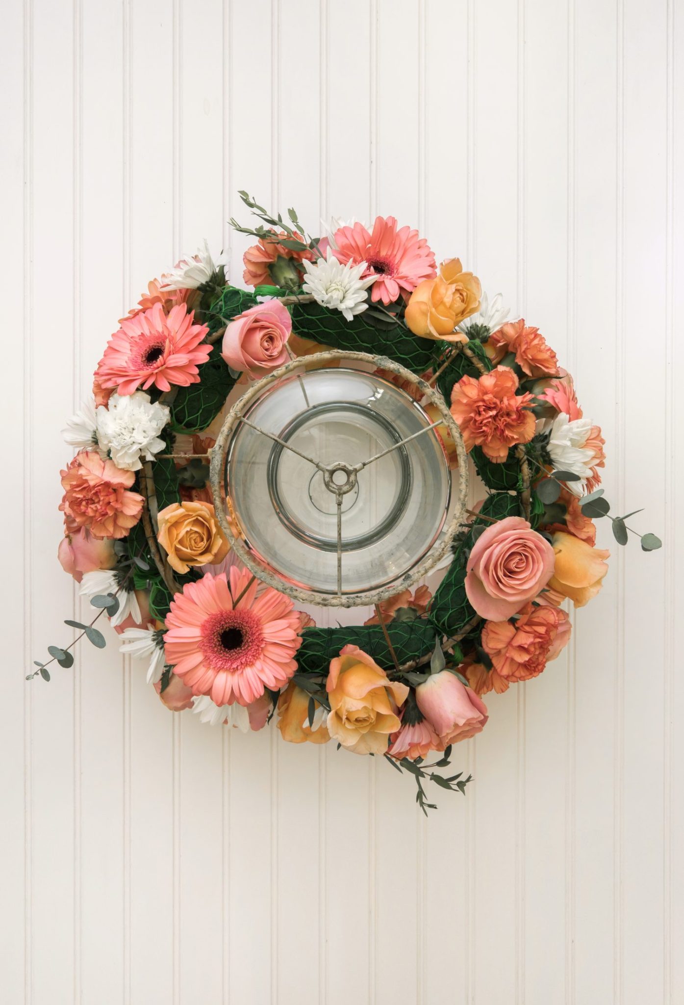 A handmade flower crown made from a vintage lampshade, oasis, and fresh flowers hanging on top of a magical table set for 40 guests.