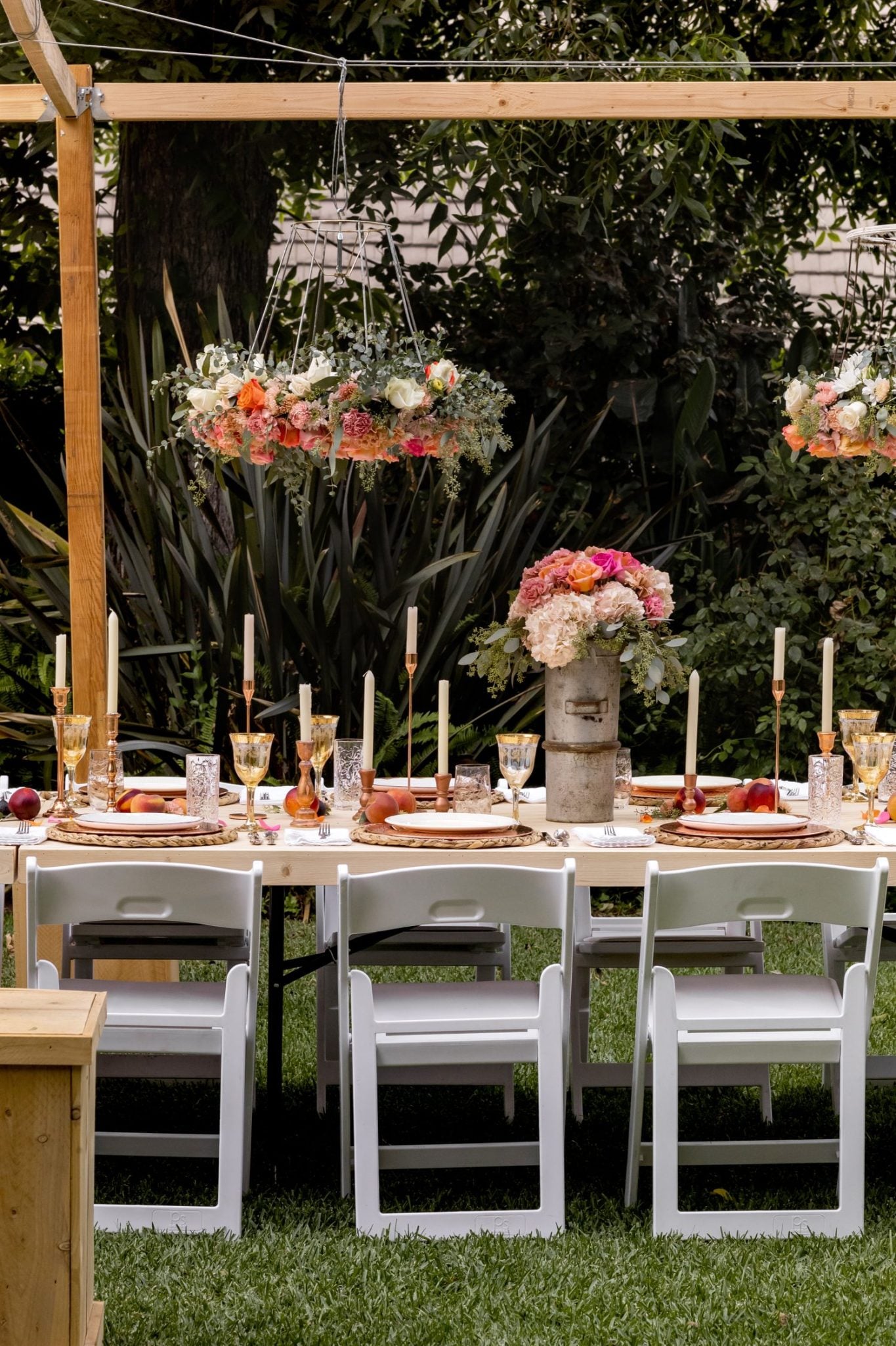 A handmade flower crown made from a vintage lampshade, oasis, and fresh flowers hanging on top of a magical table set for 40 guests.