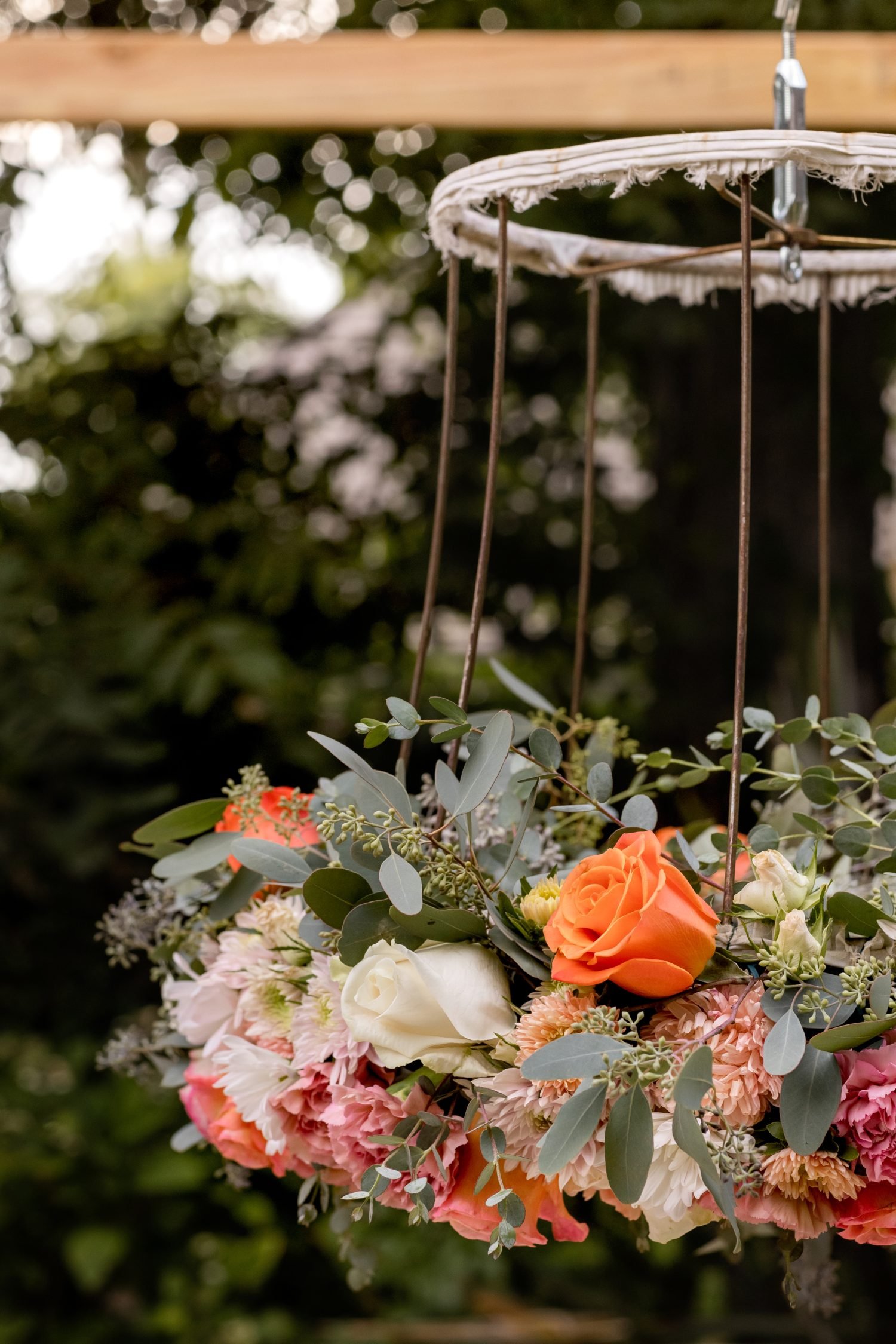 A handmade flower crown made from a vintage lampshade, oasis, and fresh flowers hanging on top of a magical table set for 40 guests.