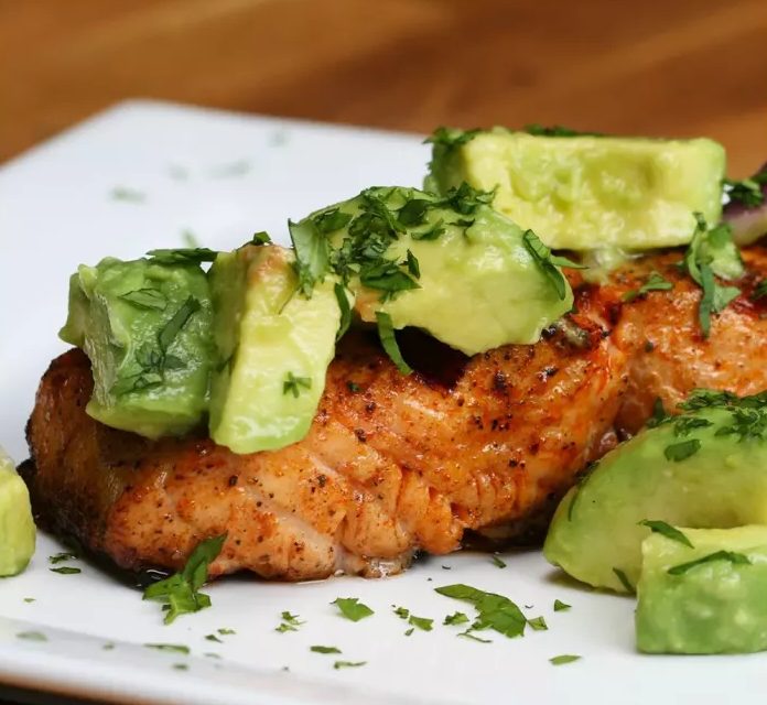 A plate with grilled salmon and avocados.
