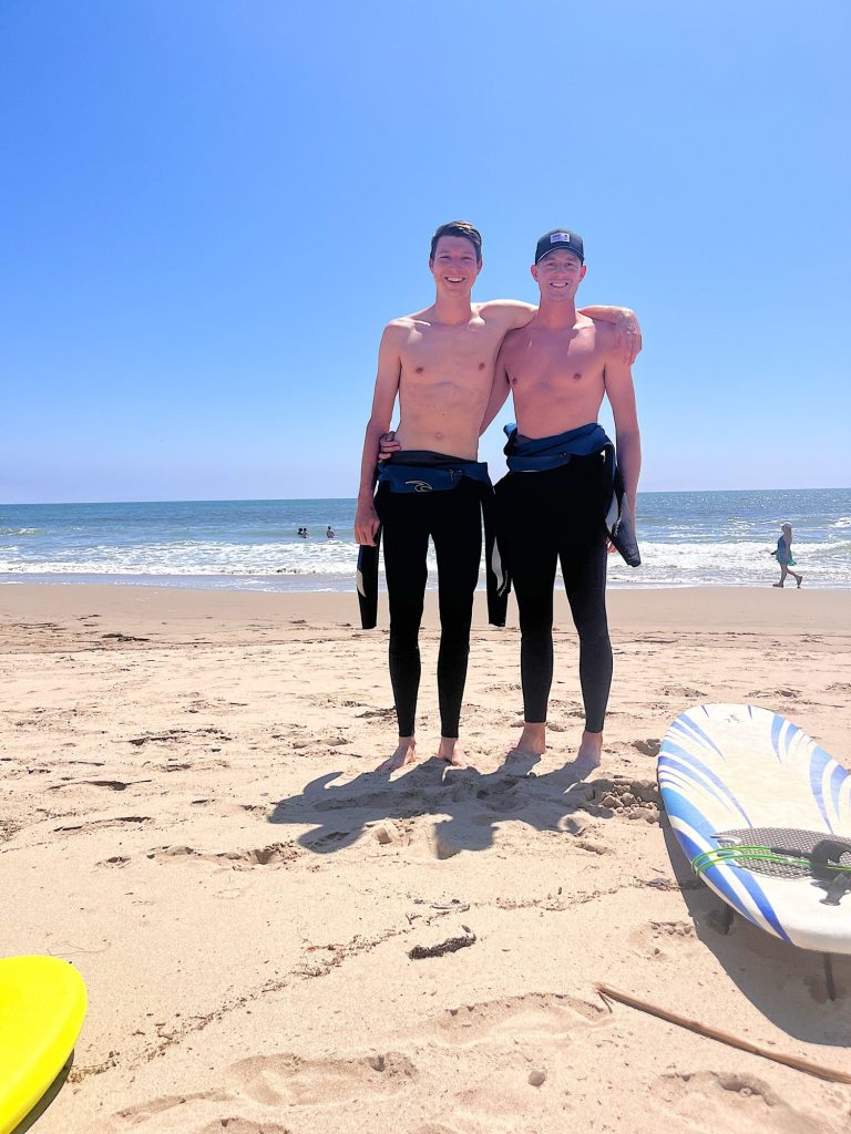 Michael and Matt wearing wetsuits after surfing