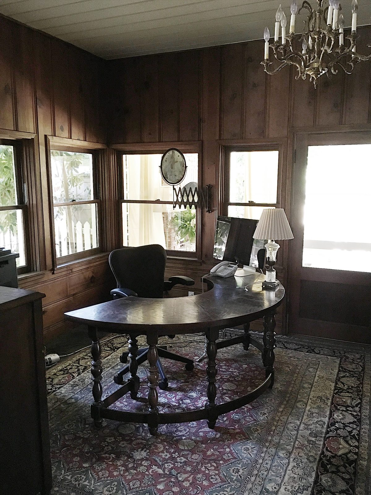 The transformation of a craft room with dark paneling to a bright white room.