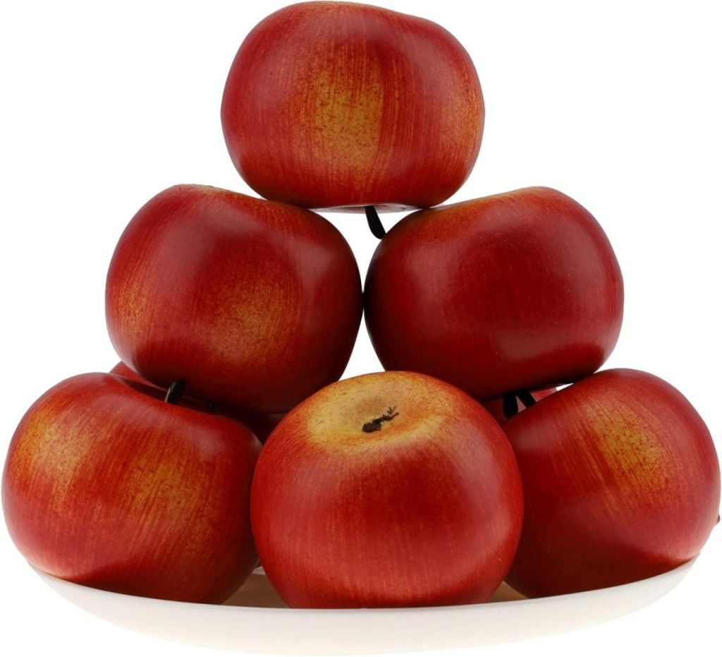 A white plate holding a stack of seven red apples serves as perfect inspiration for fall table decor ideas.