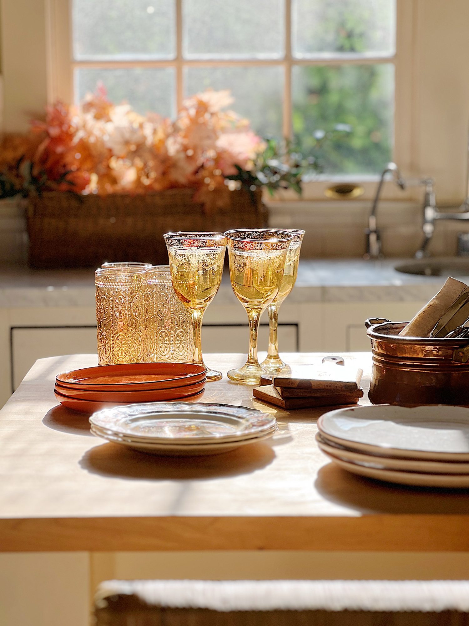 A white kitchen with an island and rattan barstools decorated with fall decor.
