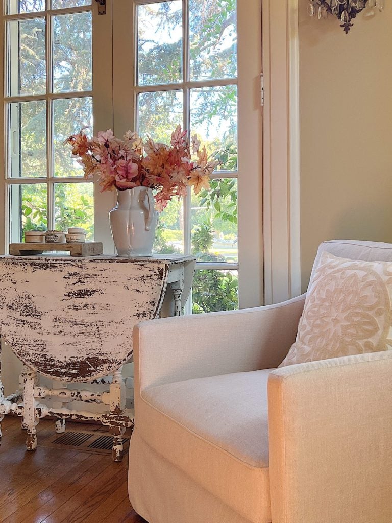 A neutral living room styled for fall with apricot, pink, and light orange florals and decor.