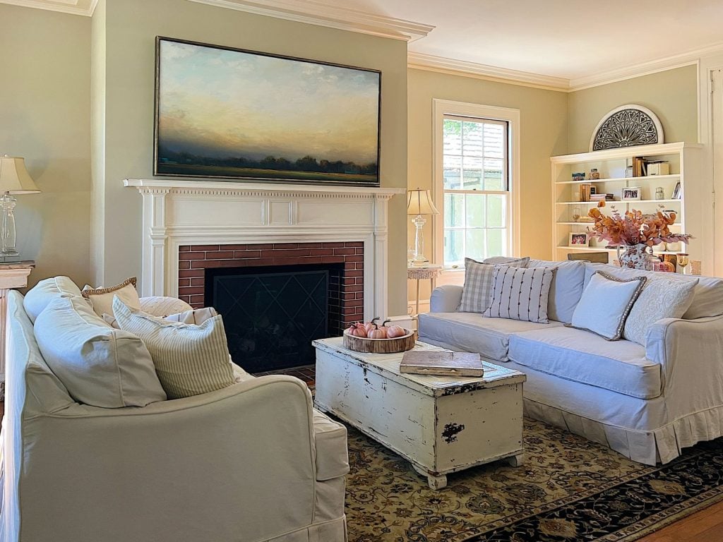 A neutral living room styled for fall with apricot, pink, and light orange florals and decor.