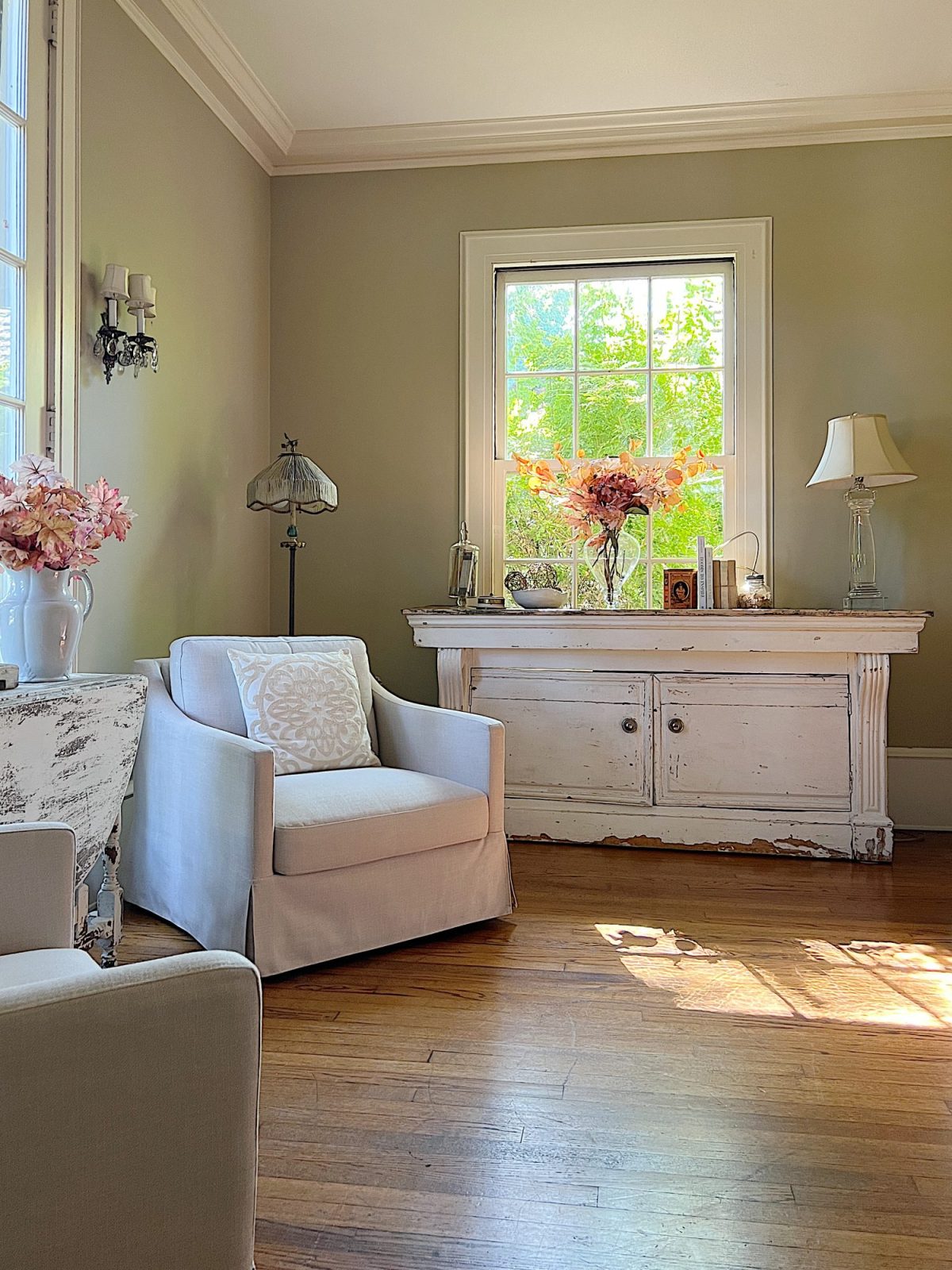 A neutral living room styled for fall with apricot, pink, and light orange florals and decor.