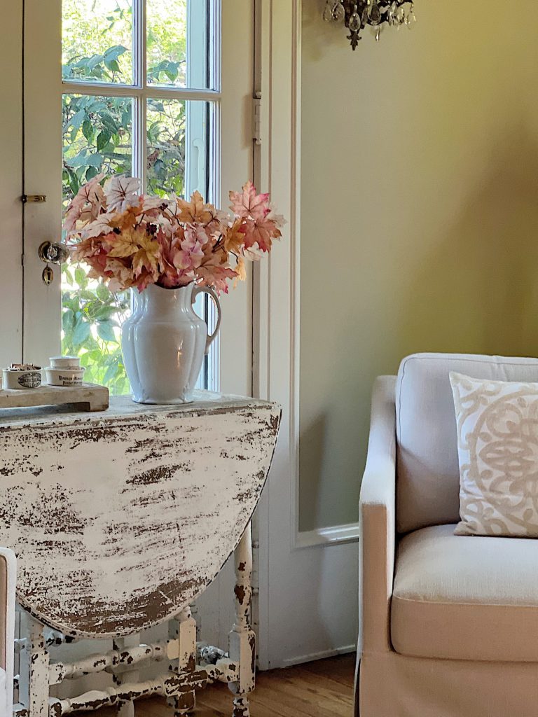 A neutral living room styled for fall with apricot, pink, and light orange florals and decor.