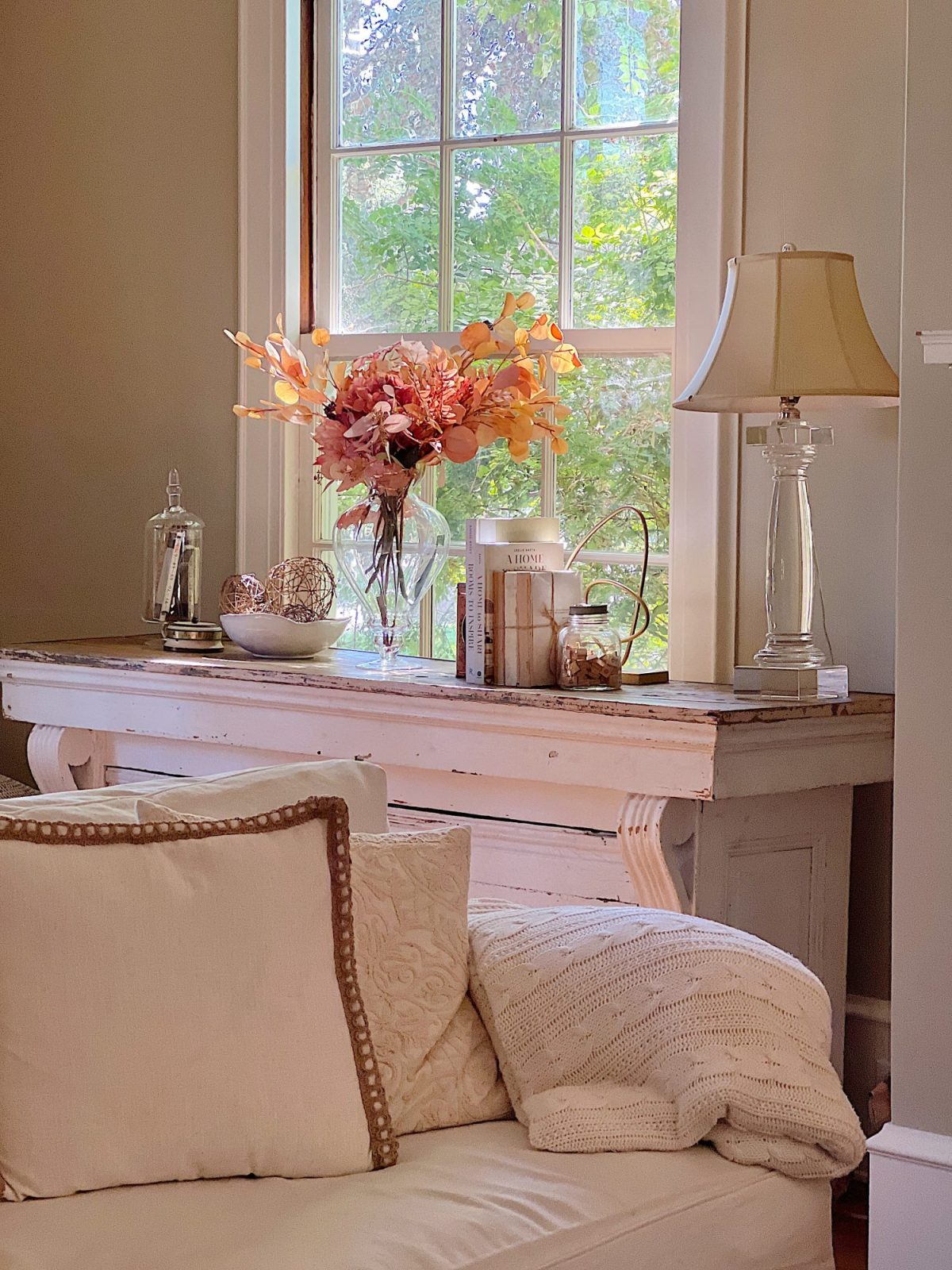 A neutral living room styled for fall with apricot, pink, and light orange florals and decor.