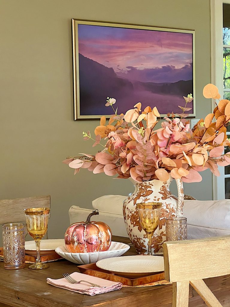 A neutral living room styled for fall with apricot, pink, and light orange florals and decor.