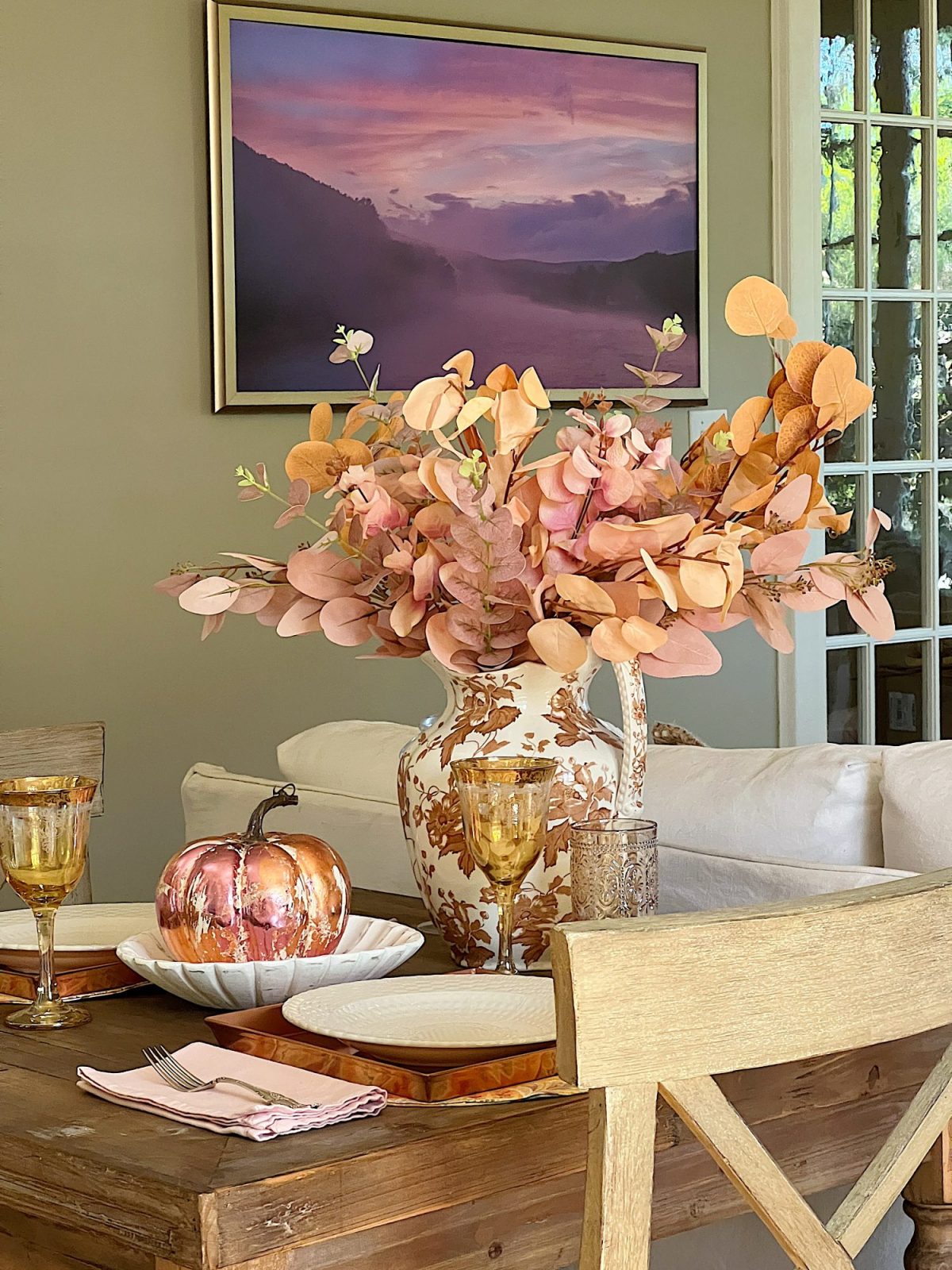 A neutral living room styled for fall with apricot, pink, and light orange florals and decor.