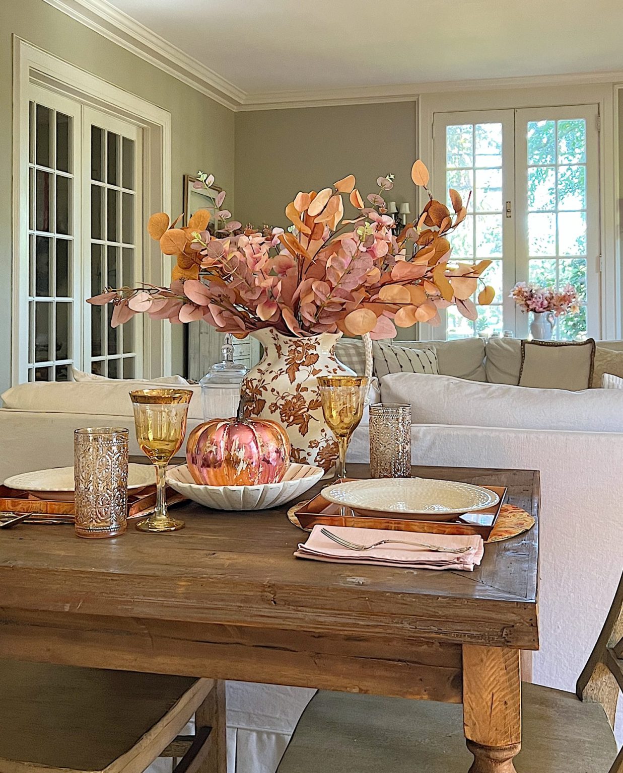 A neutral living room styled for fall with apricot, pink, and light orange florals and decor.