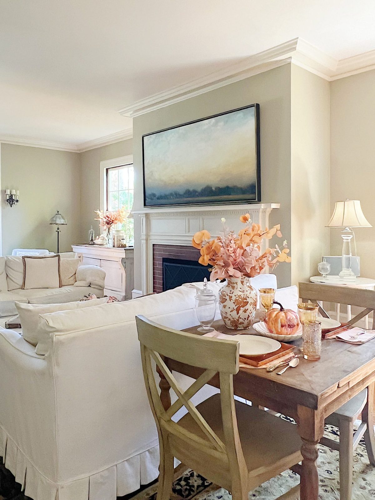 A neutral living room styled for fall with apricot, pink, and light orange florals and decor.