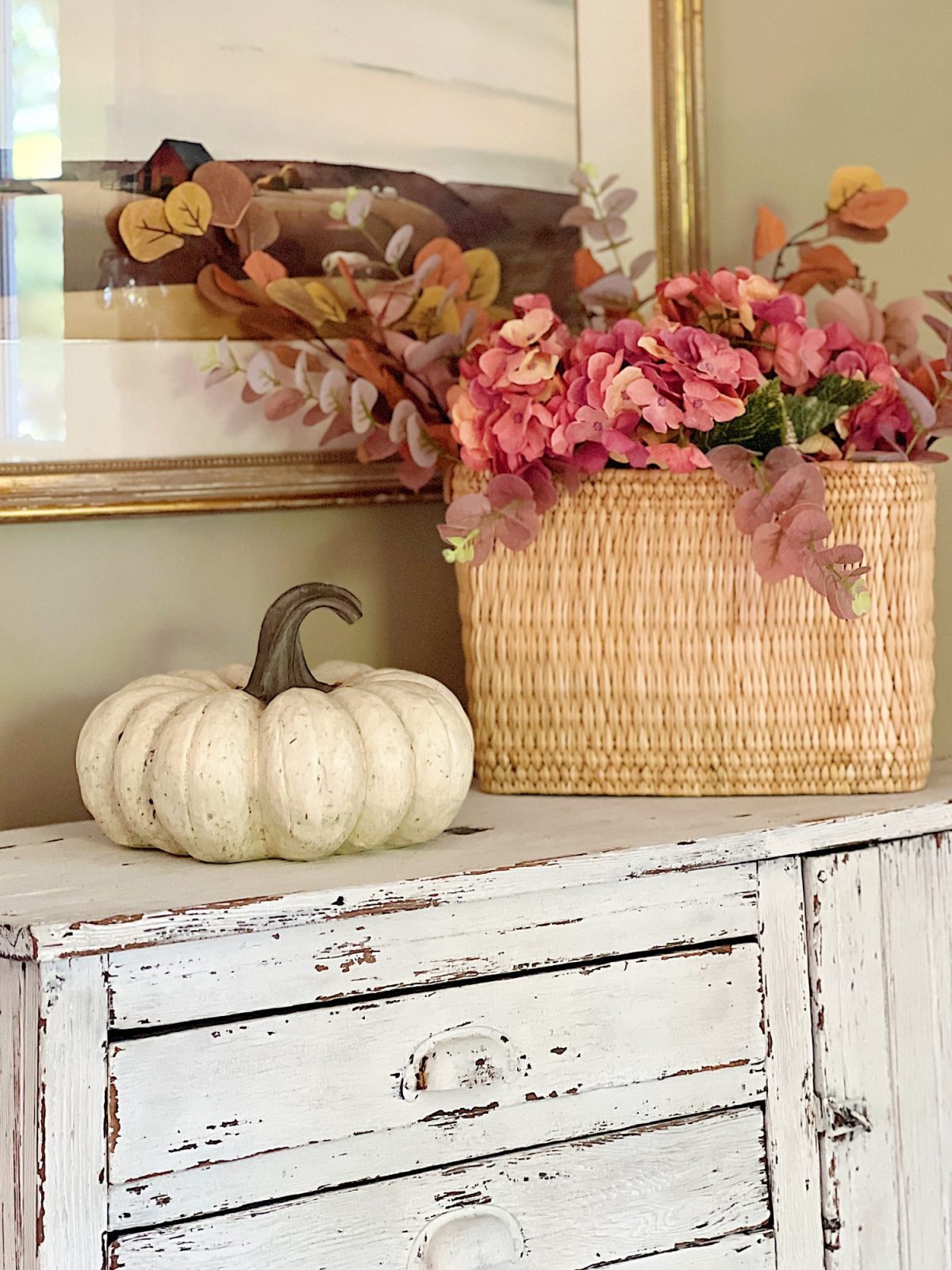 A neutral living room styled for fall with apricot, pink, and light orange florals and decor.