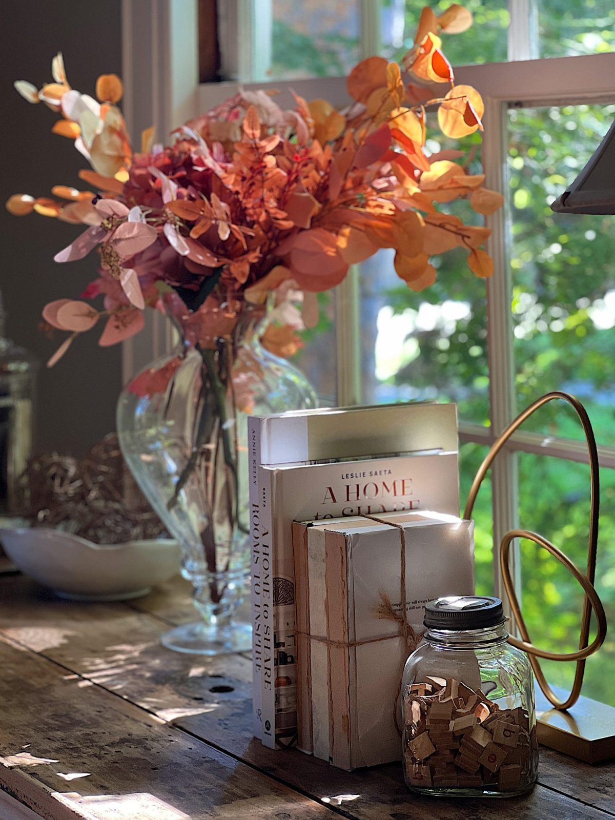 A neutral living room styled for fall with apricot, pink, and light orange florals and decor.