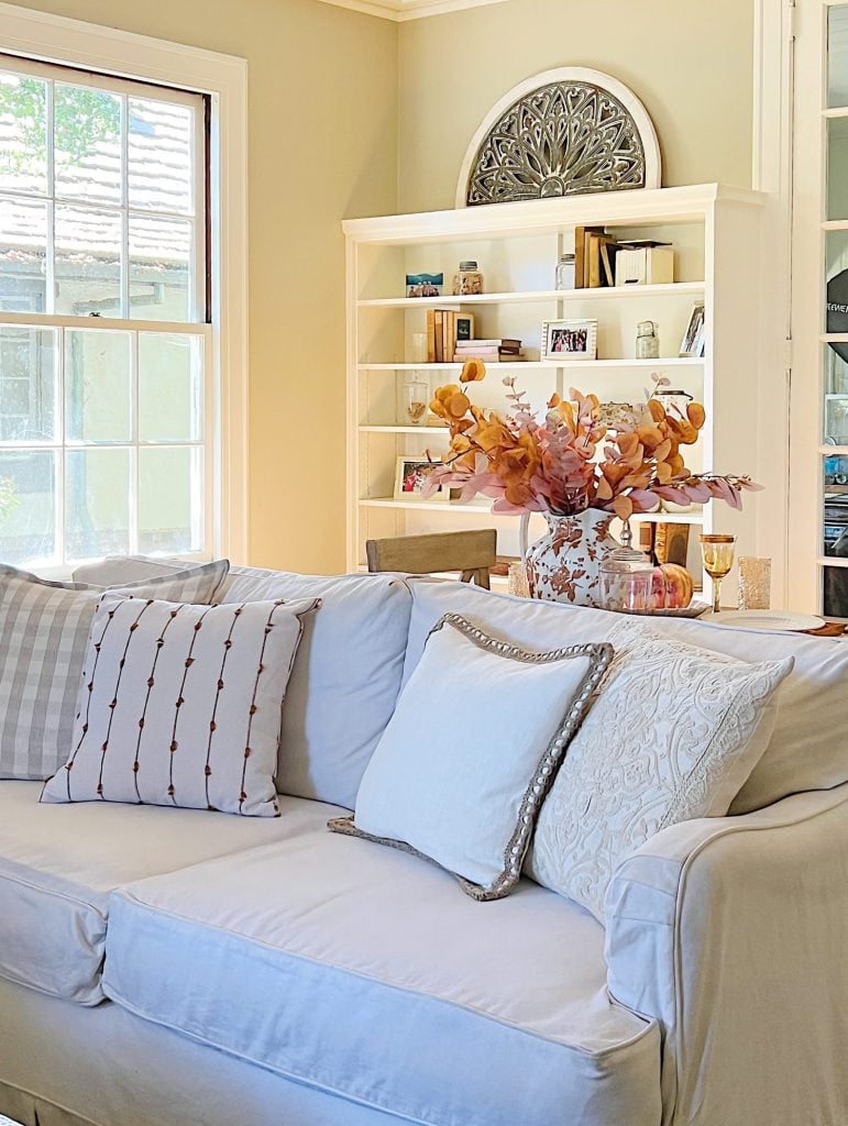 A neutral living room styled for fall with apricot, pink, and light orange florals and decor.