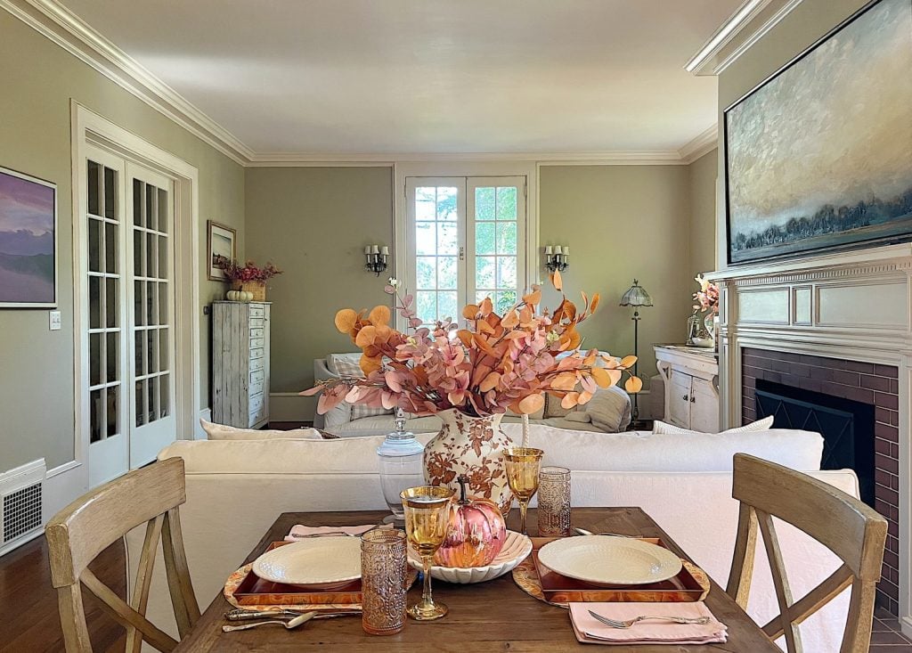 A neutral living room styled for fall with apricot, pink, and light orange florals and decor.