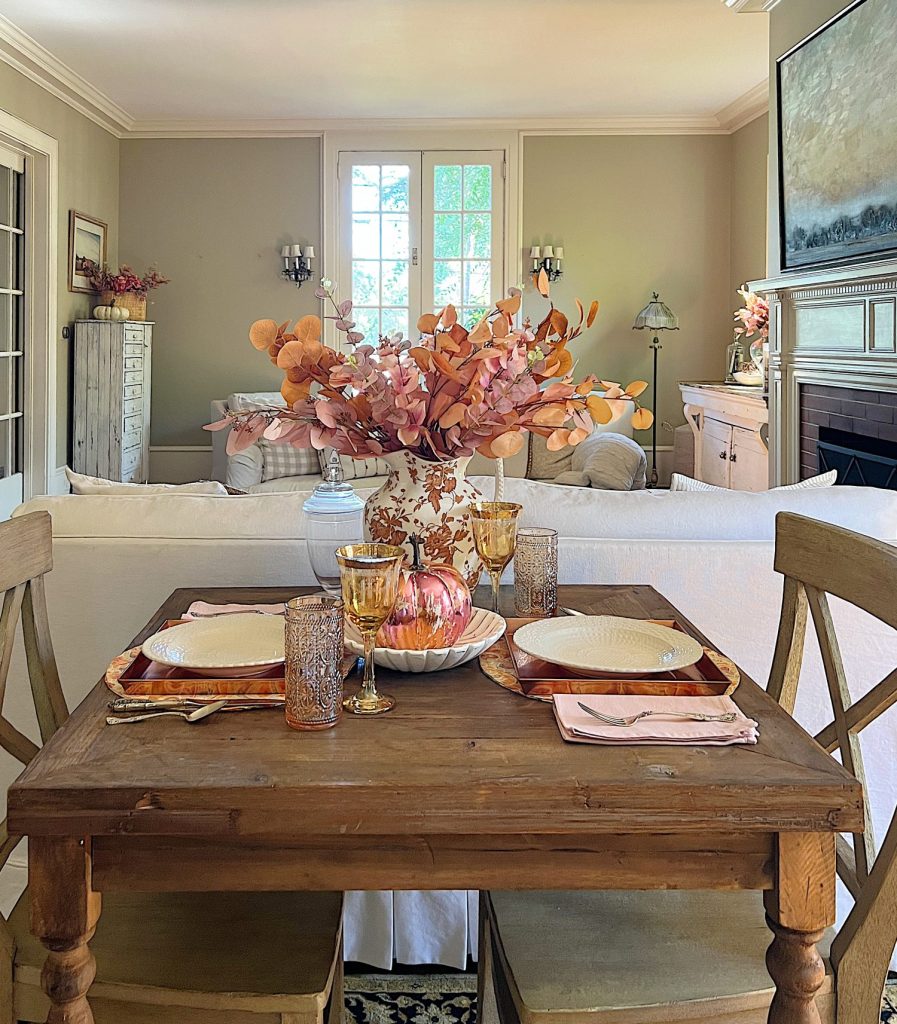 A neutral living room styled for fall with apricot, pink, and light orange florals and decor.