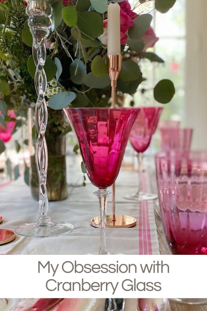 Vintage cranberry glass on a table set in pink and white tones.