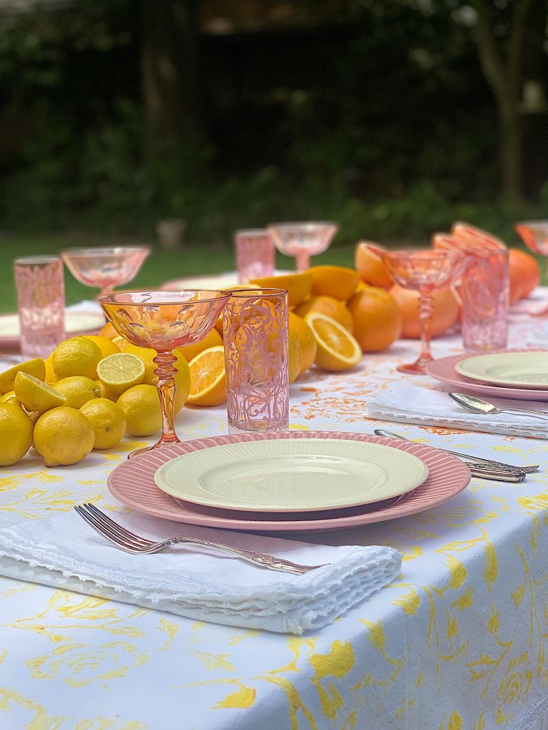 A late summer table with a painted tablecloth and lots of citrus.