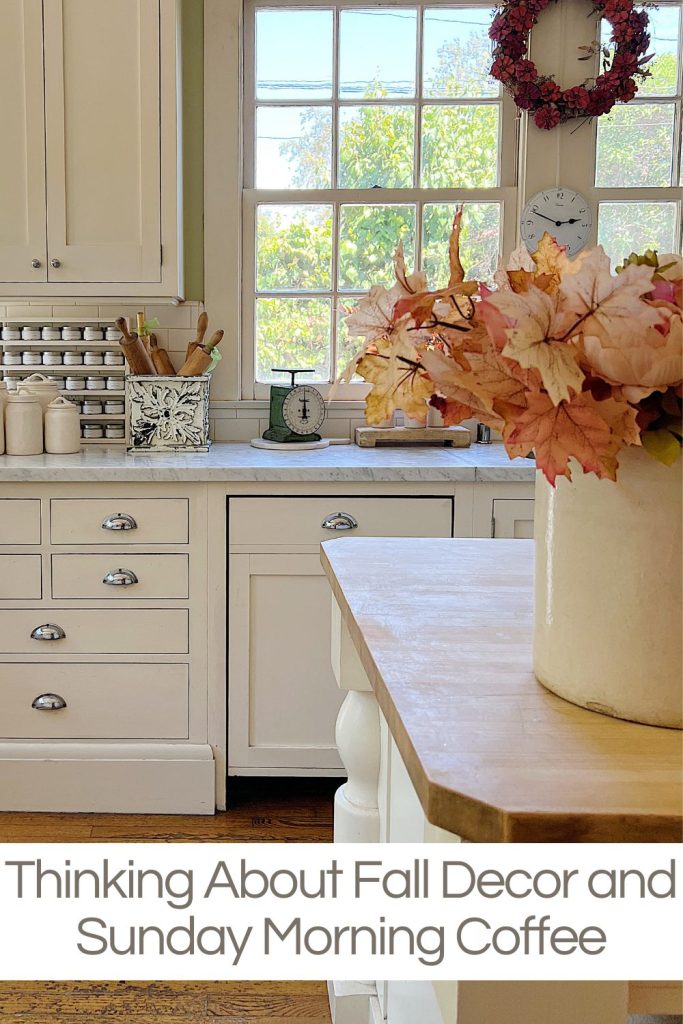 A white farmhouse kitchen with white cabinets, fall decor, and a butcher block island.