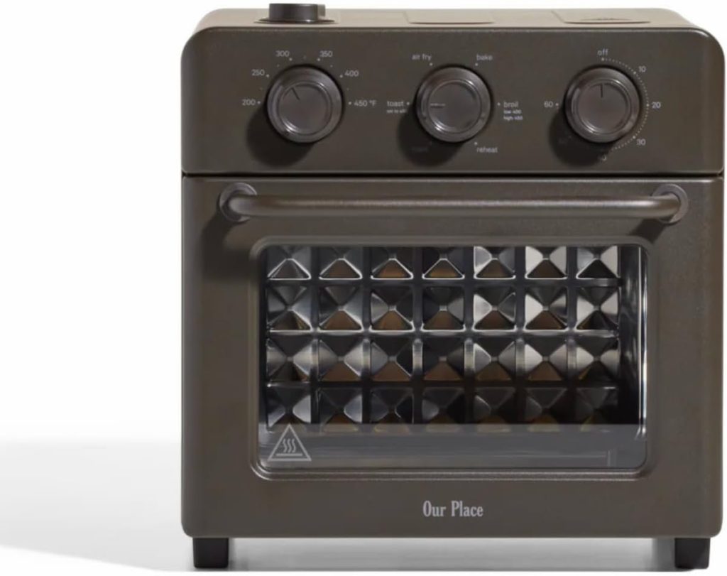 A countertop air fryer oven with three dials, a transparent front door, and the brand name "Our Place" at the bottom—perfect for whipping up quick meals like a nutritious protein bowl.