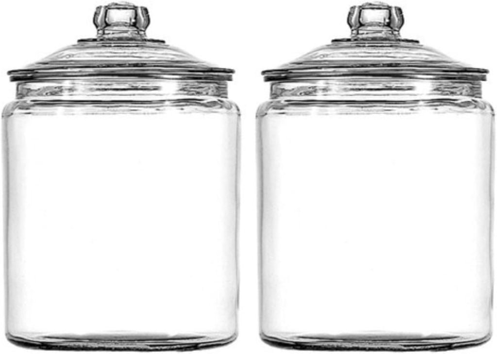 Two empty, clear glass jars with lids are placed side by side against a plain background, ready to hold the vibrant ingredients of a pear and cranberry tart.