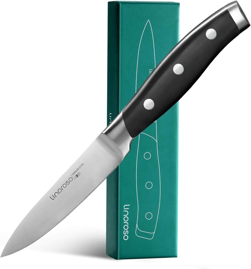 A stainless steel paring knife with a black handle is displayed alongside its green packaging box, perfect for prepping ingredients for your Halloween Wreath festivities.