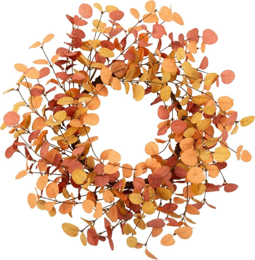 A Halloween wreath made of round, orange, and yellow leaves arranged in a circular pattern.