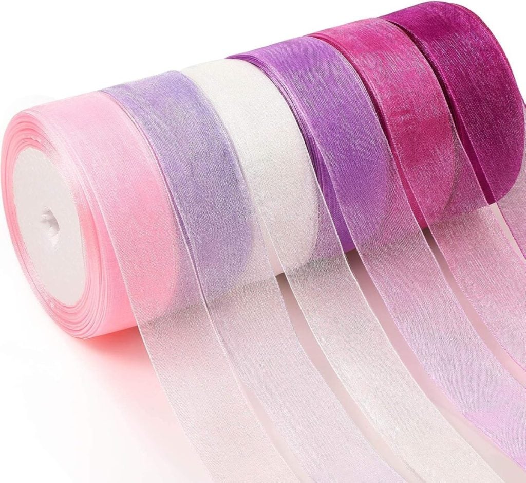 Five rolls of sheer ribbon in gradient shades of pink, purple, and white are laid side by side on a white surface, perfect for adding a delicate touch to your Halloween wreath.