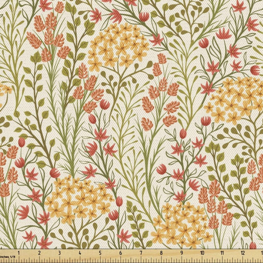 A fabric with a botanical pattern features yellow, pink, and green floral designs interspersed with fall pumpkins on a beige background, with a ruler at the bottom for scale.