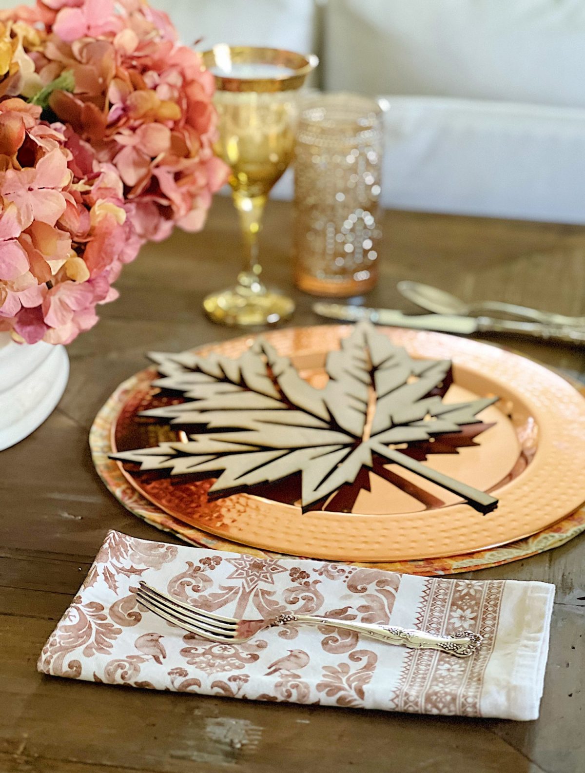 A fall themed table with a placemat, copper charger, amber glassware and a fall leaf wood charger cut with a laser cutting machine.