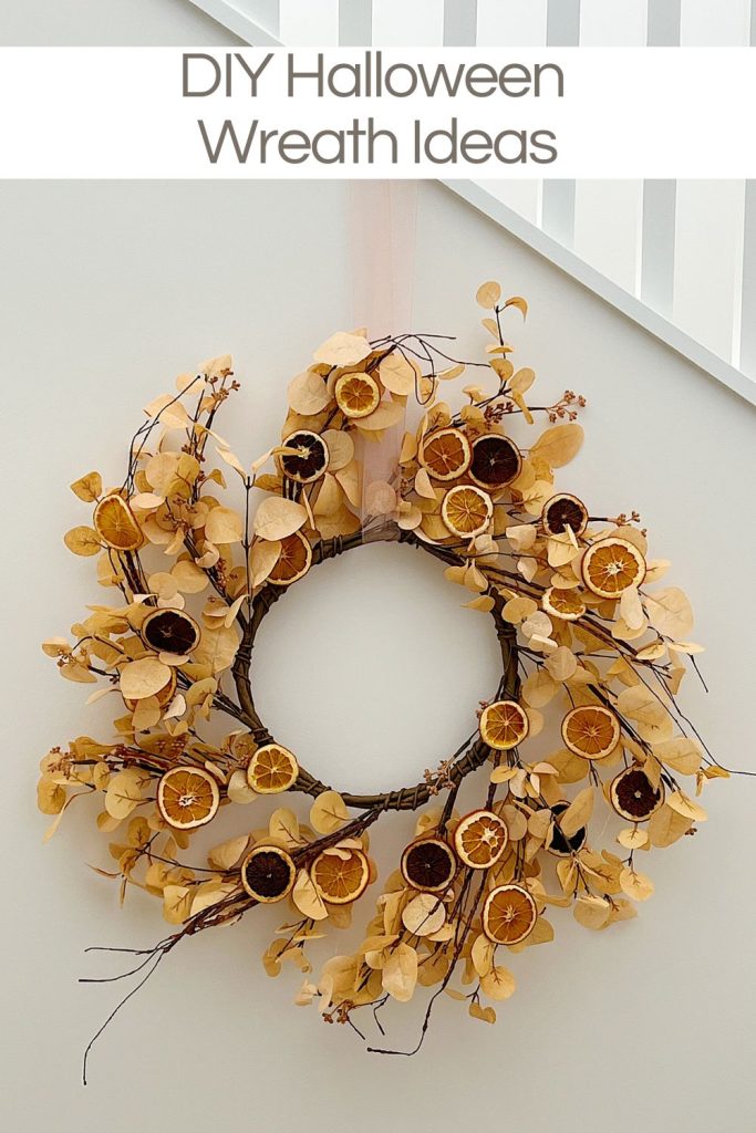 A DIY Halloween wreath made with a eucalyptus wreath and dried orange slices.