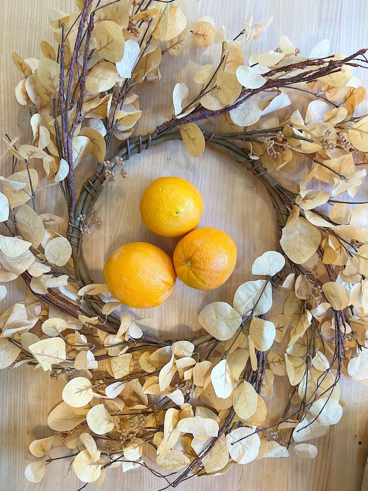 A DIY Halloween wreath made with a eucalyptus wreath and dried orange slices.