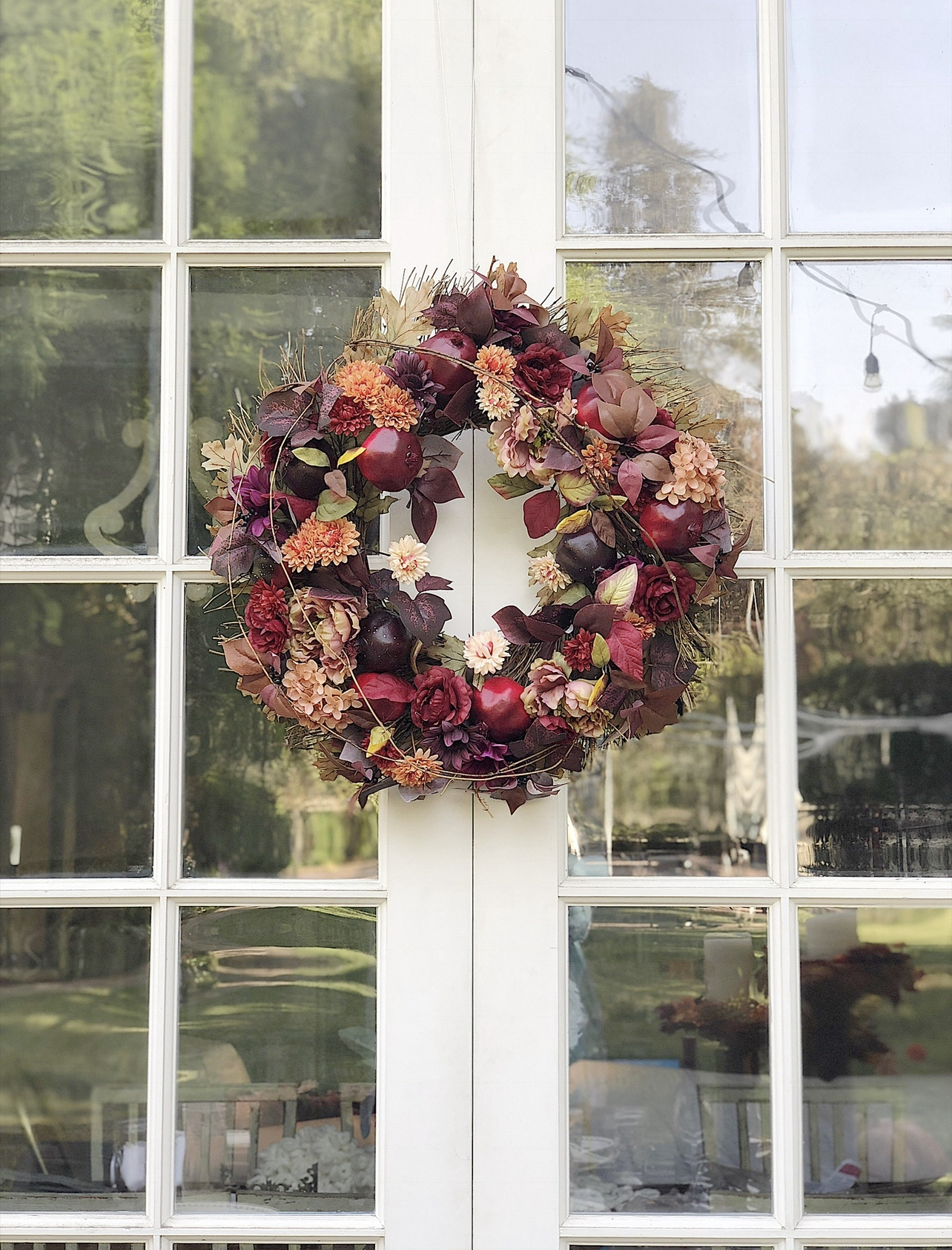 A fall table set on a back porch wtrh gorgeous faux florals, portmeirion plates, and a charcuterie board.