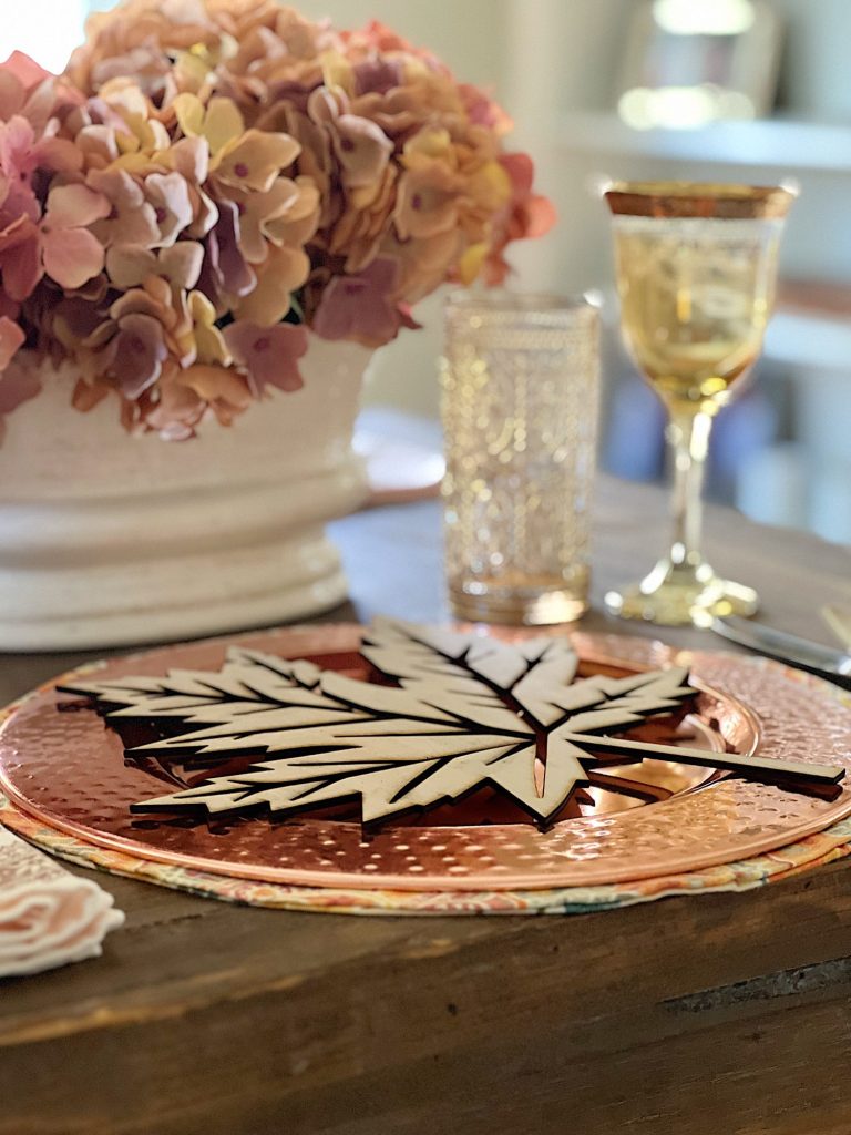 A fall themed table with a placemat, copper charger, amber glassware and a fall leaf wood charger cut with a laser cutting machine.