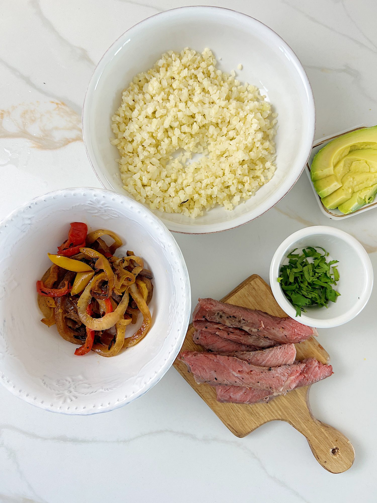 The best beef protein bowl with cauliflower rice, sauted onions and tomatoes, avocado, and fresh cilantro.