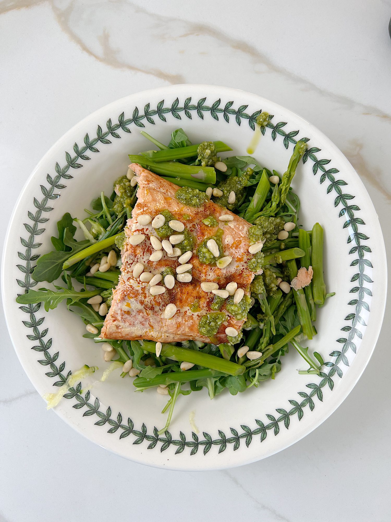 The best salmon protein bowl with arugula, grated zucchii, steamed asparagus, pesto, and pine nuts..