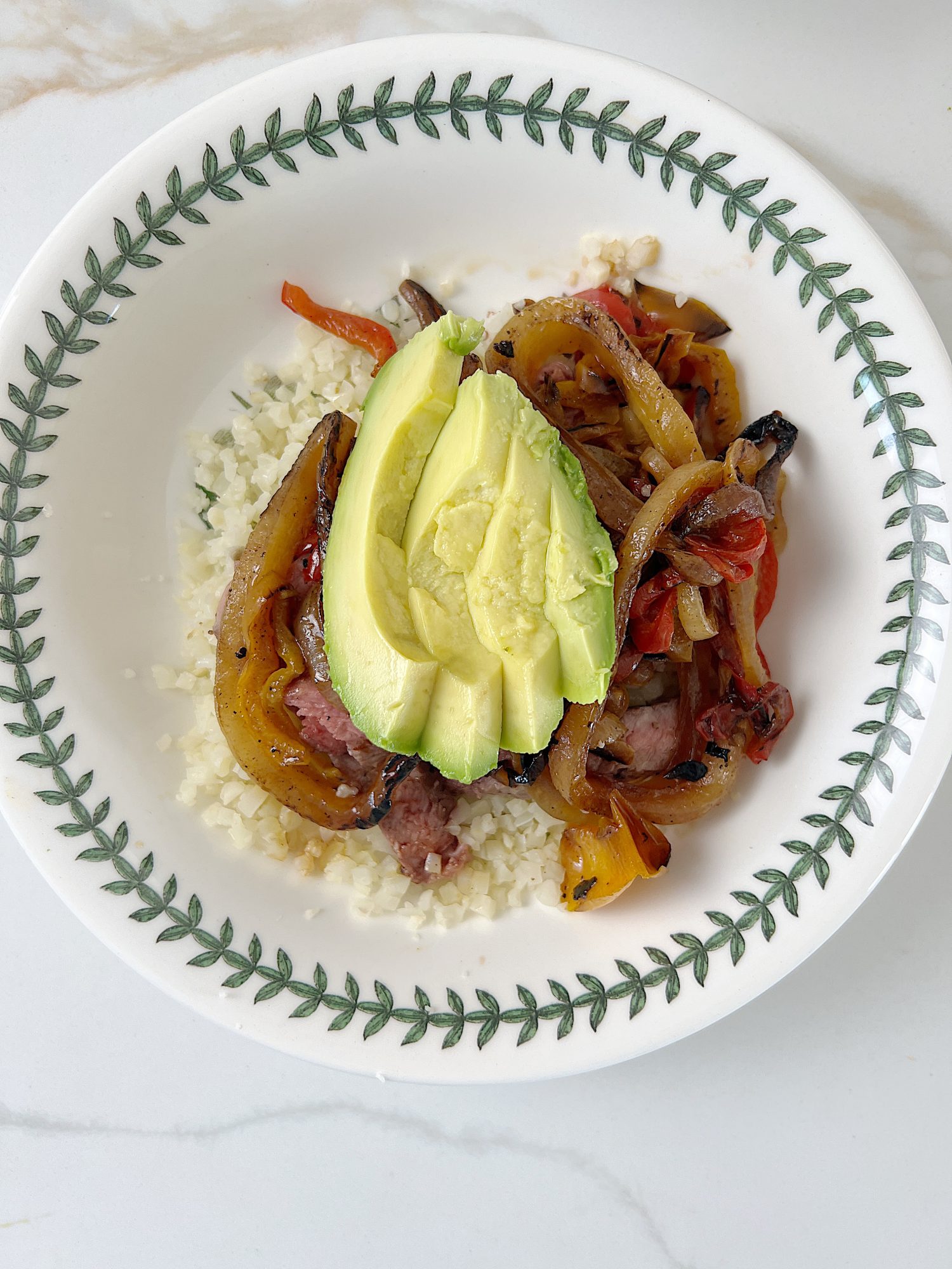 The best beef protein bowl with cauliflower rice, sauted onions and tomatoes, avocado, and fresh cilantro.