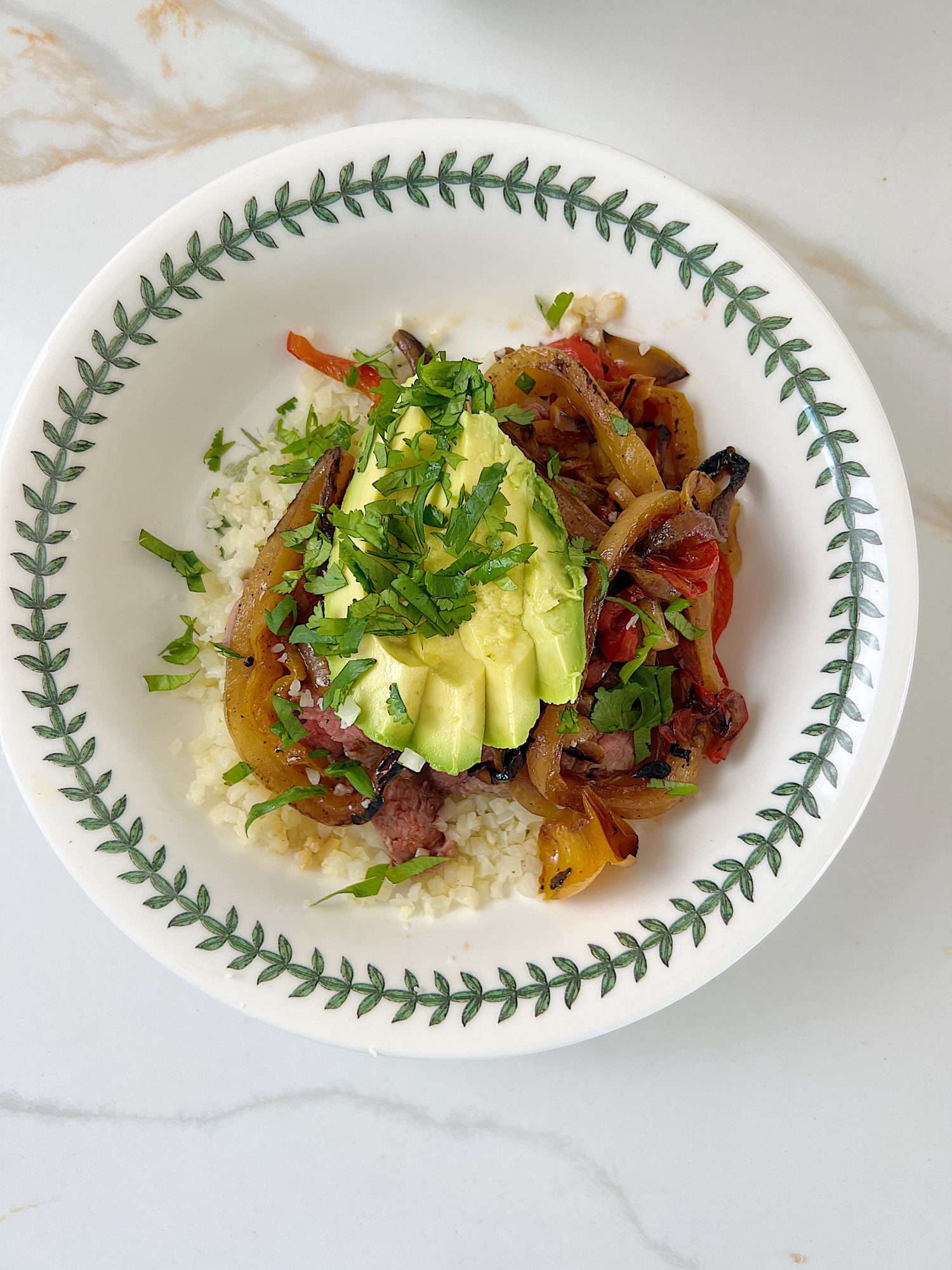 The best beef protein bowl with cauliflower rice, sauted onions and tomatoes, avocado, and fresh cilantro.