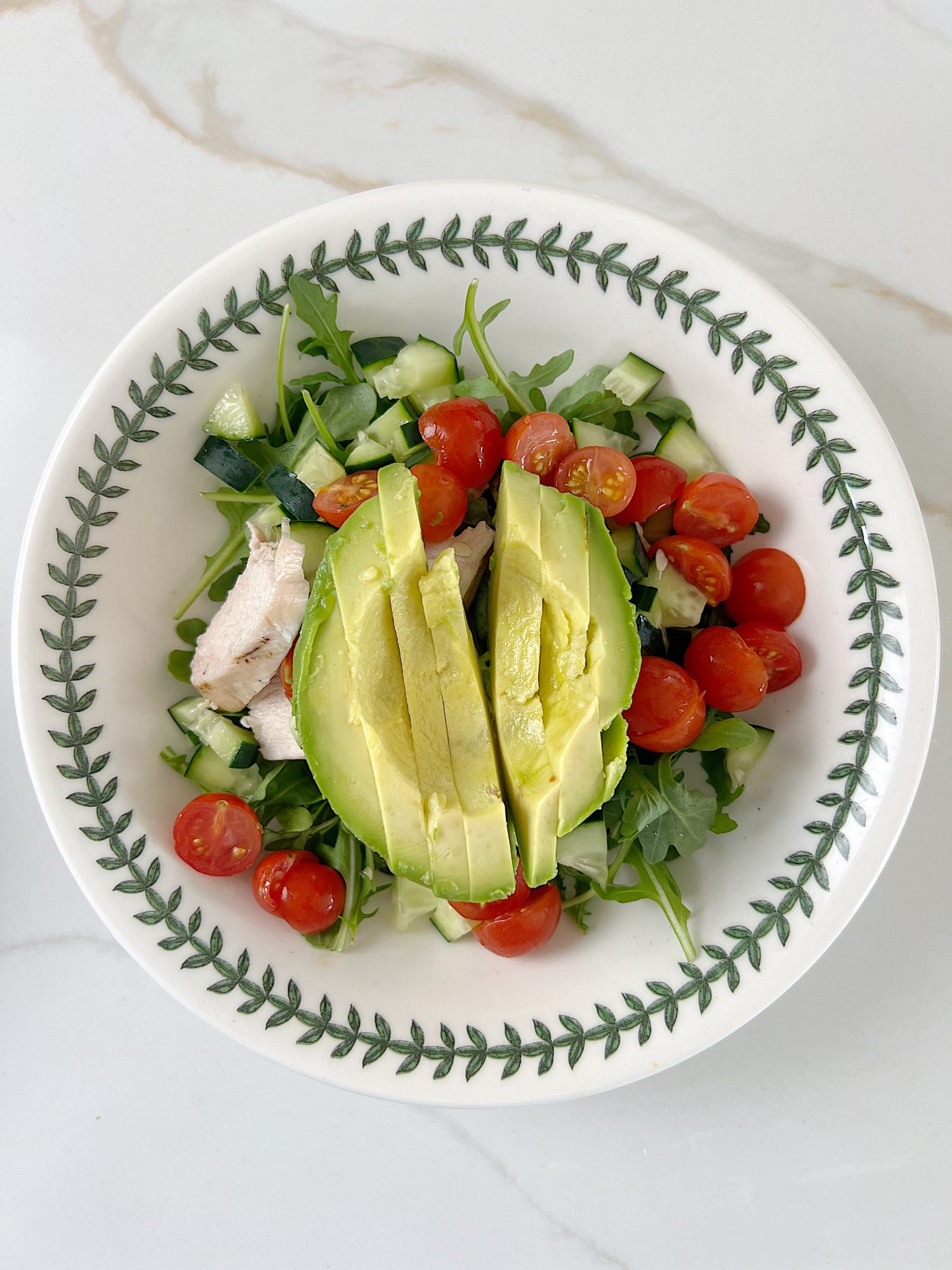 The best chicken protein bowl with arugula, tomatoes, cucumbers, avocado, and gorgonzola.