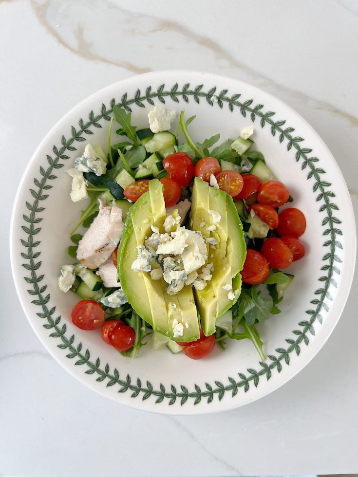 The best chicken protein bowl with arugula, tomatoes, cucumbers, avocado, and gorgonzola.