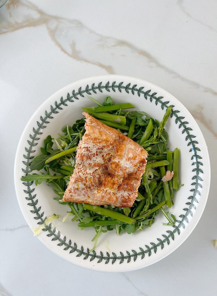 The best salmon protein bowl with arugula, grated zucchii, steamed asparagus, pesto, and pine nuts..