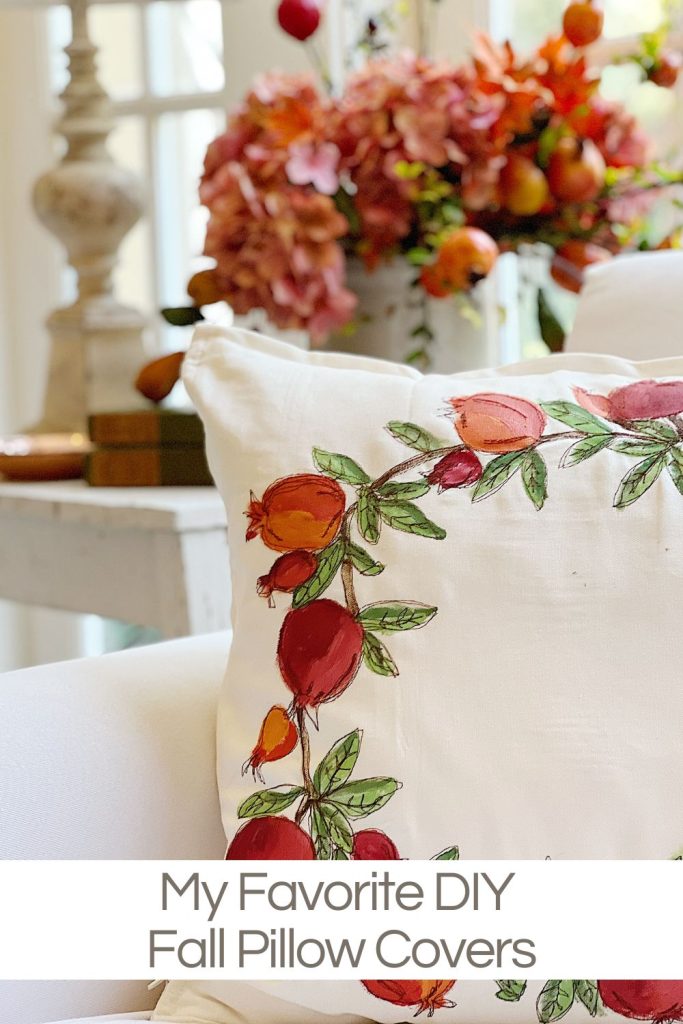 A handmade pillow cover with painted and stitched pomegranates in reds, oranges, and pinks.