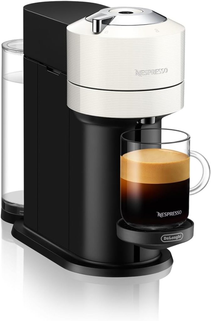 A Nespresso coffee machine with a black body, white top, and a clear water container attached. It is brewing a cup of coffee that sits on a small tray, perfect for pairing with some freshly baked Halloween sugar cookies.