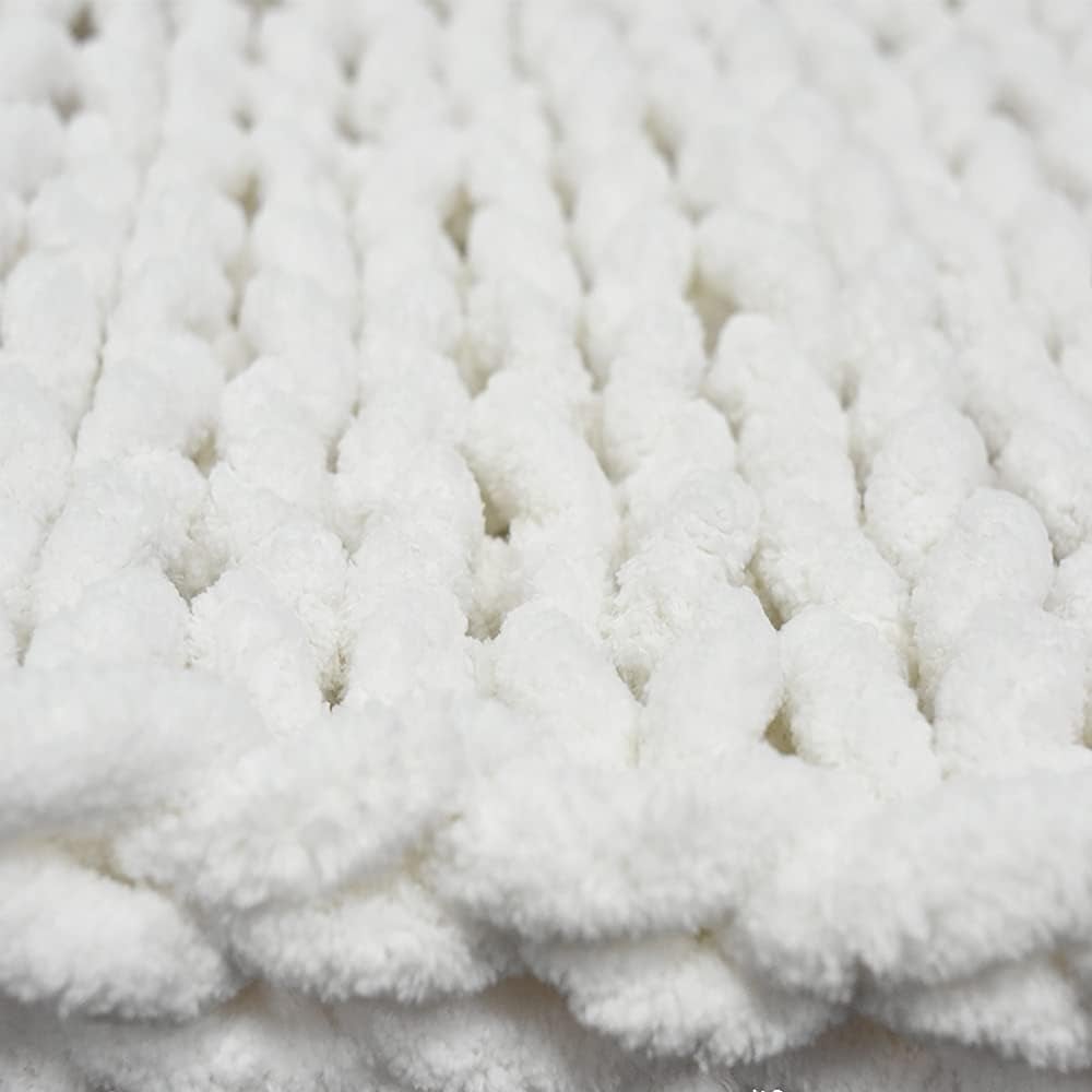 Close-up of a white, thickly knitted fall blanket with textured loops.