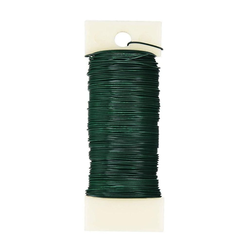 A spool of green gardening wire, perfect for crafting your Thanksgiving wreath, wrapped around a white holder.