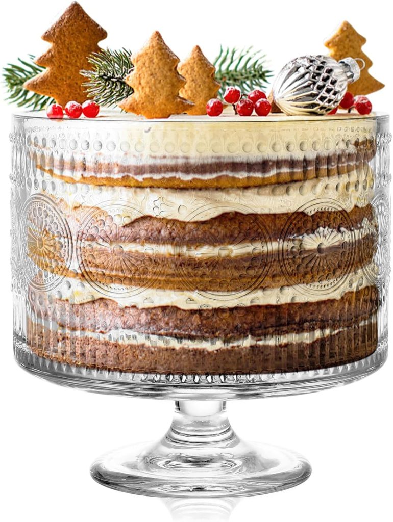 Layered trifle cake with cream and brown cake layers in a clear glass dish, topped with gingerbread cookies, red berries, evergreen sprigs, and a silver ornament—a festive take on the classic Pumpkin Trifle Recipe.